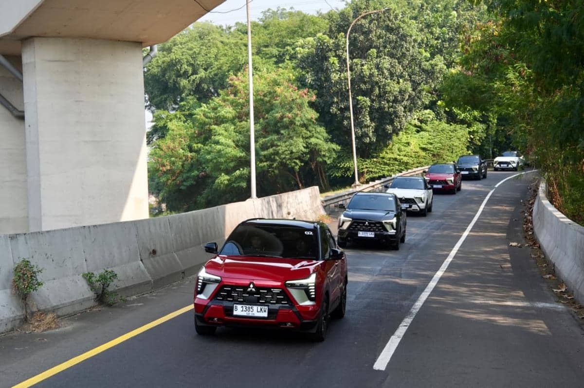 Beberapa unit Mitsubishi New Xforce HEV melaju beriringan di jalan raya saat kegiatan test drive di area dengan pepohonan rindang.