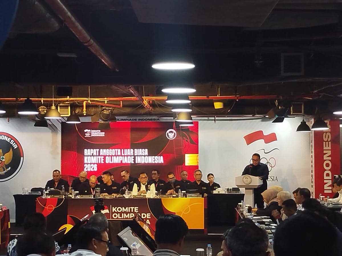 Suasana Rapat Anggota Luar Biasa Komite Olimpiade Indonesia dengan peserta duduk di meja konferensi dan pembicara di podium.