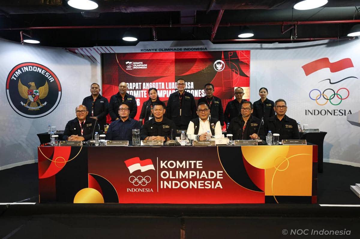 Para anggota Komite Olimpiade Indonesia berpose bersama dalam Rapat Anggota Luar Biasa NOC Indonesia di ruangan dengan latar logo Olimpiade.