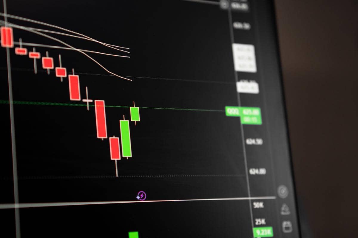 Grafik candlestick merah dan hijau pada layar komputer yang menampilkan pergerakan harga saham untuk analisis pasar.