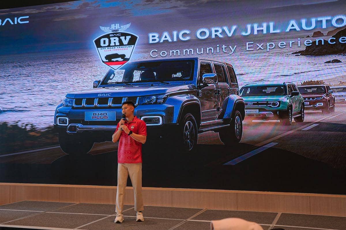 Seorang pria berbicara di atas panggung dengan latar belakang layar besar menampilkan mobil BAIC ORV dan logo JHL Auto.