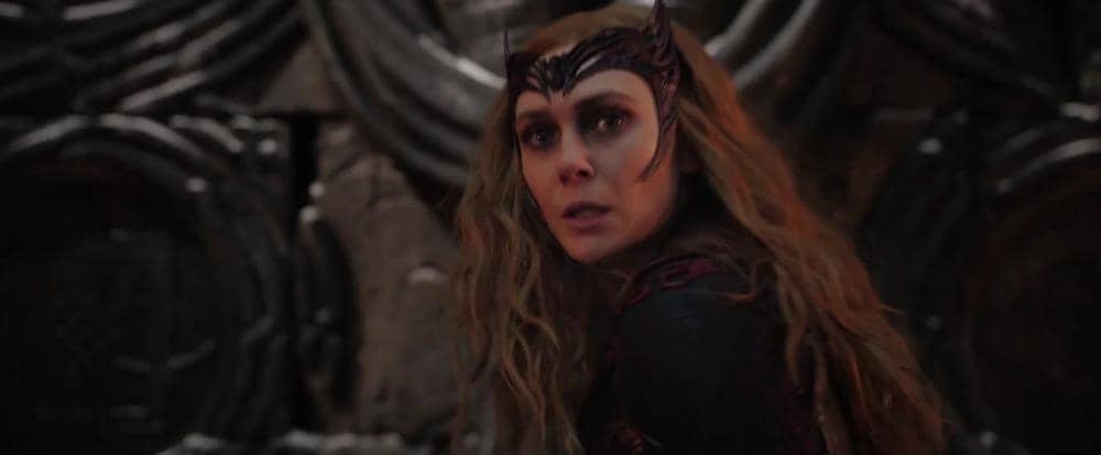 Wanda Maximoff mengenakan kostum merah gelap dengan mahkota hitam, berdiri di latar gelap dalam adegan film Doctor Strange in the Multiverse of Madness.