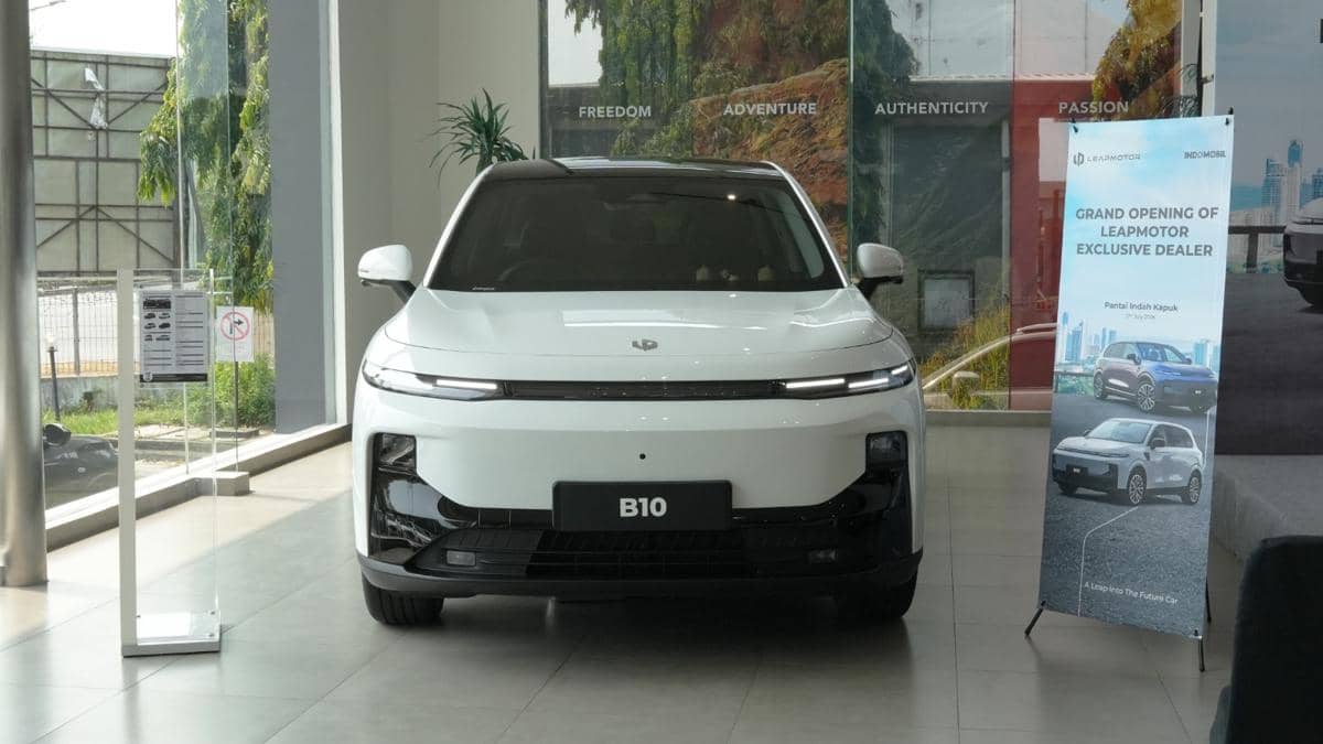 Mobil listrik Leapmotor B10 berwarna putih dipamerkan di dalam showroom dengan latar belakang spanduk pembukaan dealer eksklusif.