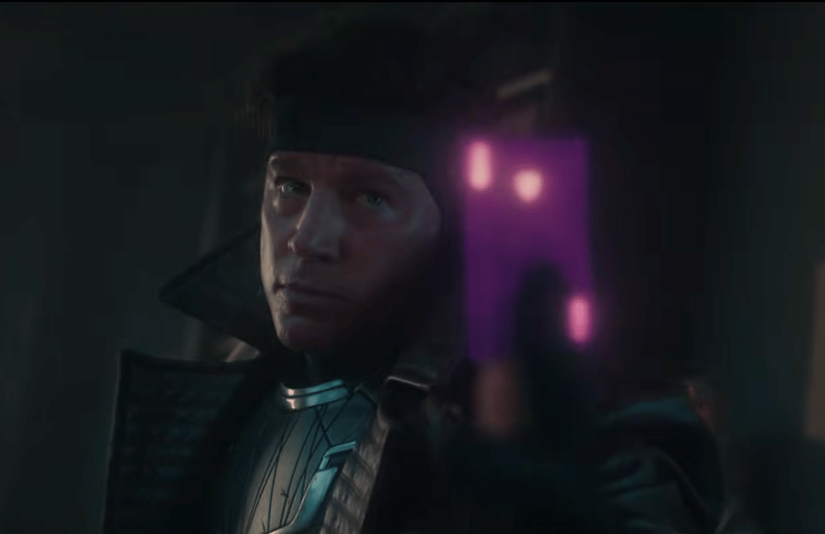Gambit mengenakan pakaian tempur gelap sambil memegang kartu bercahaya ungu dalam adegan film Avengers: Doomsday.