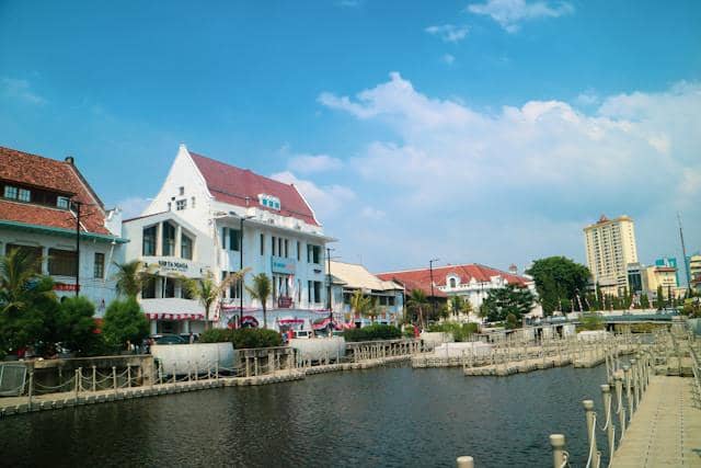 Bangunan bergaya kolonial di tepi kanal dengan langit cerah di kawasan Kota Tua Jakarta yang menjadi destinasi wisata bersejarah.