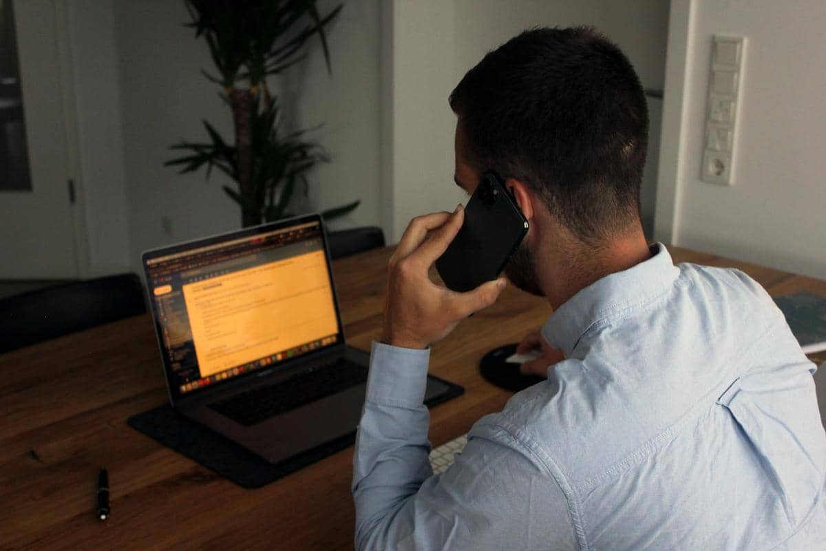 Seorang pria memeriksa informasi melalui laptop saat melakukan panggilan telepon 
