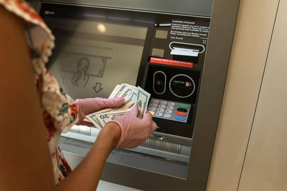 Potret seseorang yang menarik uang tunai dari mesin ATM