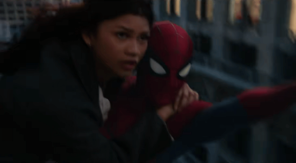 MJ berpegangan erat pada Spider-Man saat mereka berayun di antara gedung-gedung kota dalam adegan film Spider-Man: No Way Home.