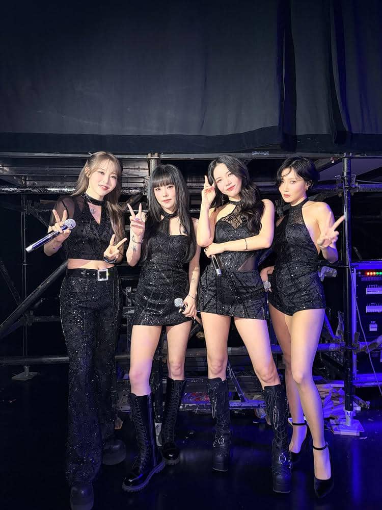 Empat anggota grup MAMAMOO berpose di belakang panggung konser 4WARD di Makau 2026 dengan busana hitam berkilau.