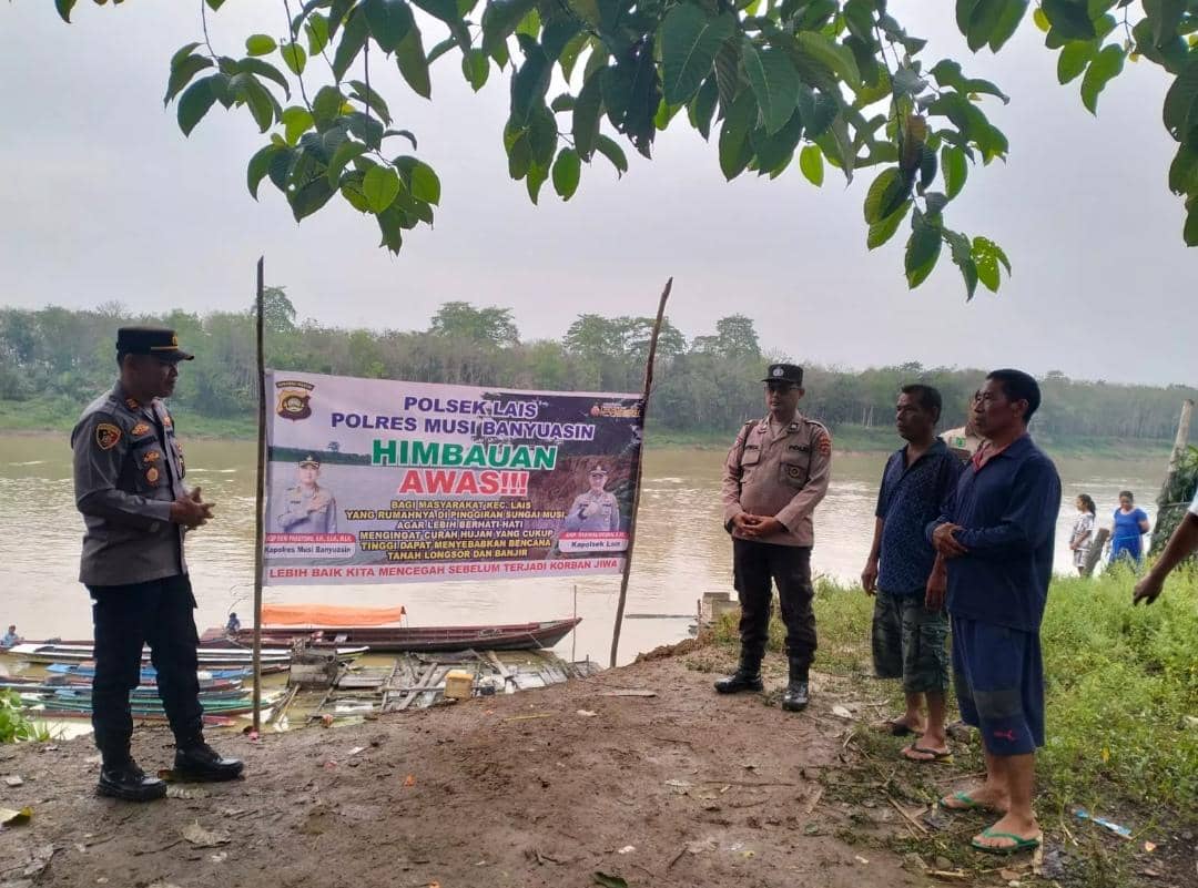 Personel Polsek Lais memasang banner peringatan di tepian Sungai Musi.