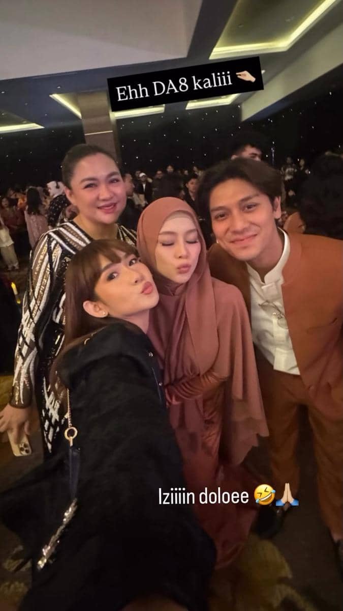 Empat orang berpose bersama di acara resepsi pernikahan dengan suasana meriah di dalam ruangan yang dipenuhi tamu undangan.