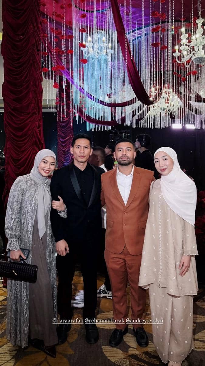 Empat tamu berpose bersama di resepsi pernikahan dengan dekorasi mewah bernuansa merah dan ungu serta lampu gantung kristal.