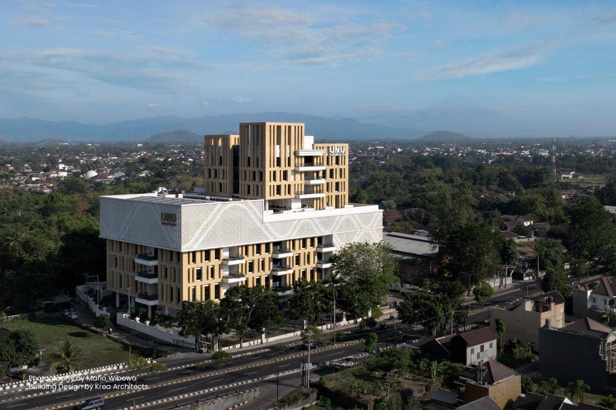 Gedung Universitas Nahdlatul Ulama Yogyakarta dengan desain modern berwarna krem dan putih, dikelilingi area hijau dan permukiman kota.