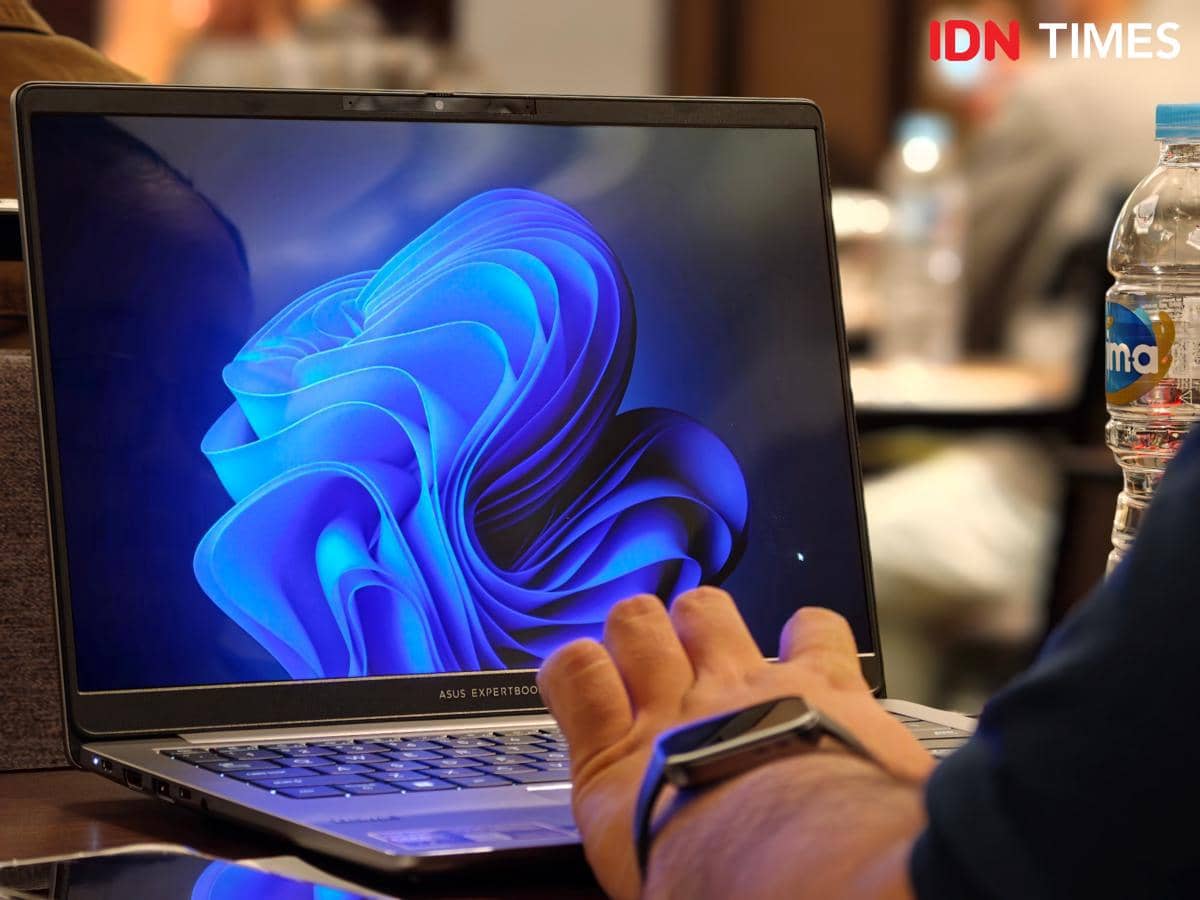 Seseorang menggunakan laptop ASUS ExpertBook P5 G2 dengan layar menampilkan tampilan Windows berwarna biru di atas meja.