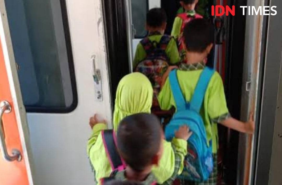 Anak-anak berseragam hijau dengan tas ransel berwarna cerah sedang naik ke dalam gerbong kereta api untuk kegiatan edukasi.