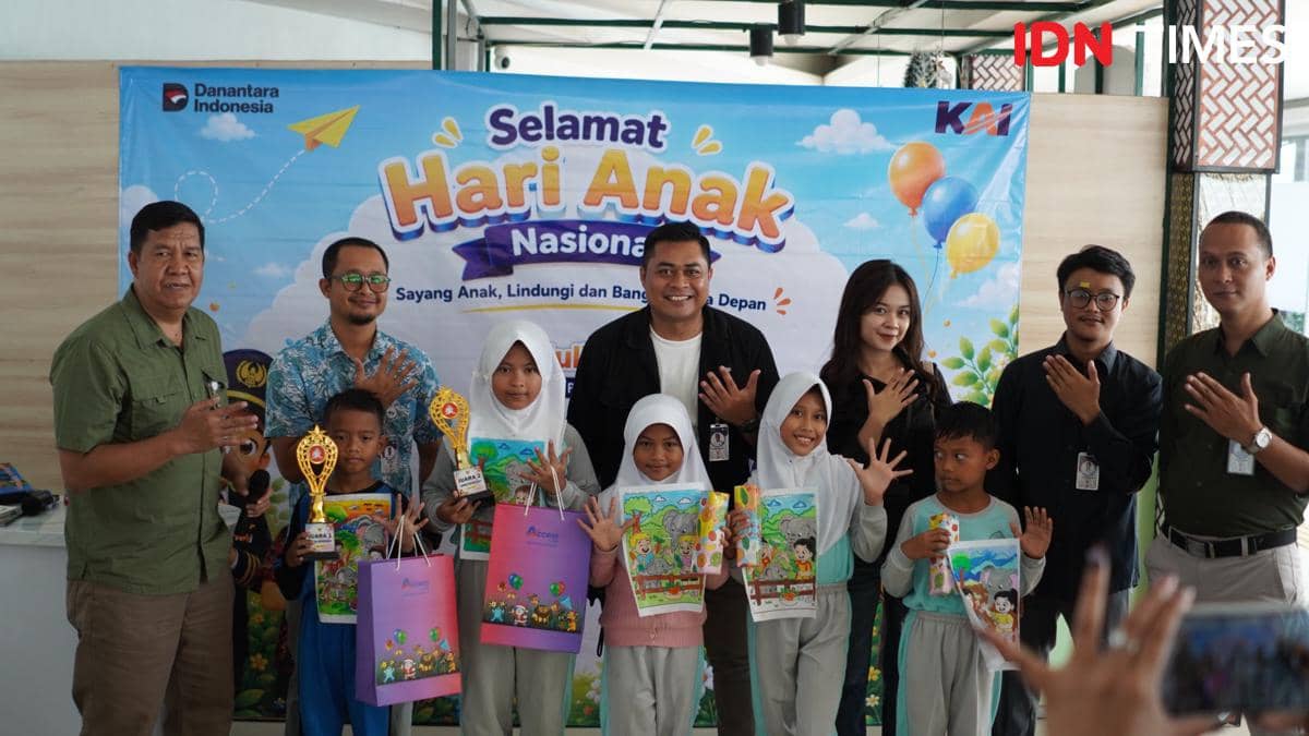 Pegawai KAI dan anak-anak sekolah berpose bersama sambil memegang hadiah dan piala dalam perayaan Hari Anak Nasional di Stasiun Purwokerto.