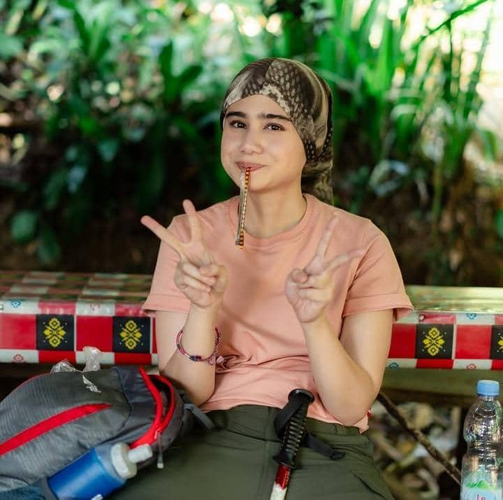 Potret Tissa Biani saat trekking menuju Curug Sentul dengan latar suasana alam hijau di kawasan wisata.