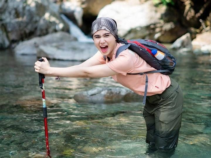 Potret Tissa Biani saat trekking menuju Curug Sentul dalam kegiatan menikmati suasana alam terbuka di kawasan tersebut.