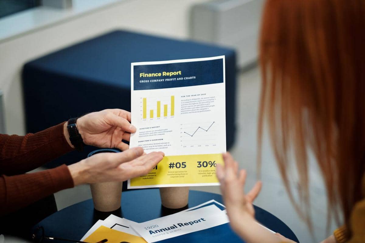 ilustrasi dua orang menganalisis grafik laporan keuangan dalam rapat bisnis di lingkungan kantor