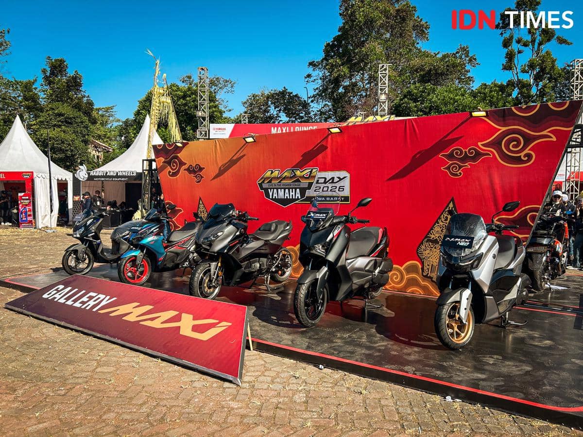 Deretan sepeda motor skuter dari lini Maxi Yamaha dipajang di area acara dengan latar dekorasi dan pencahayaan dalam ruangan.