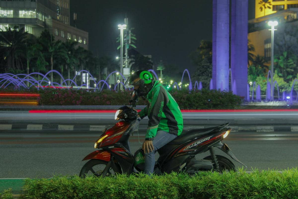 Pengemudi Gojek berhenti dengan sepeda motor di kawasan Bundaran HI pada malam hari