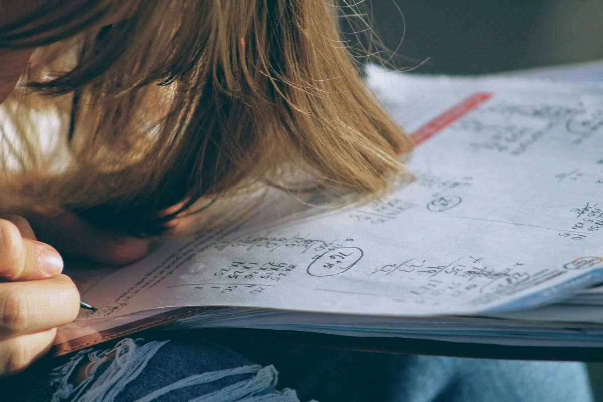Seorang siswa mengerjakan soal matematika dan menulis perhitungan pada lembar belajar