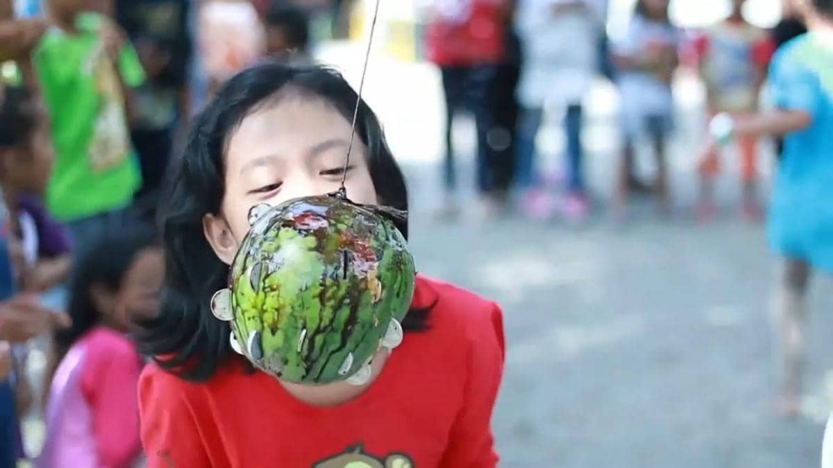 ilustrasi lomba ambil koin dalam buah semangka yang dilumuri cokelat