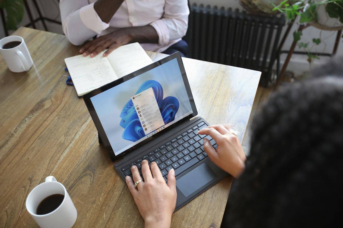 Seorang pengguna menggunakan laptop untuk mengakses layanan Microsoft, dengan layar perangkat menyala di atas meja kerja.