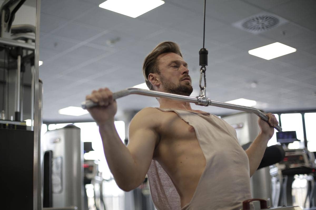 seorang pria menjaga form dan postur tubuh yang benar saat latihan lat pulldown di gym