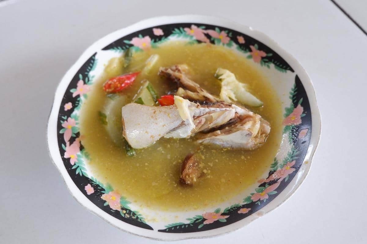 Ilustrasi gangan asam, hidangan berkuah yang disajikan dalam mangkuk dengan potongan ikan dan aneka sayuran.