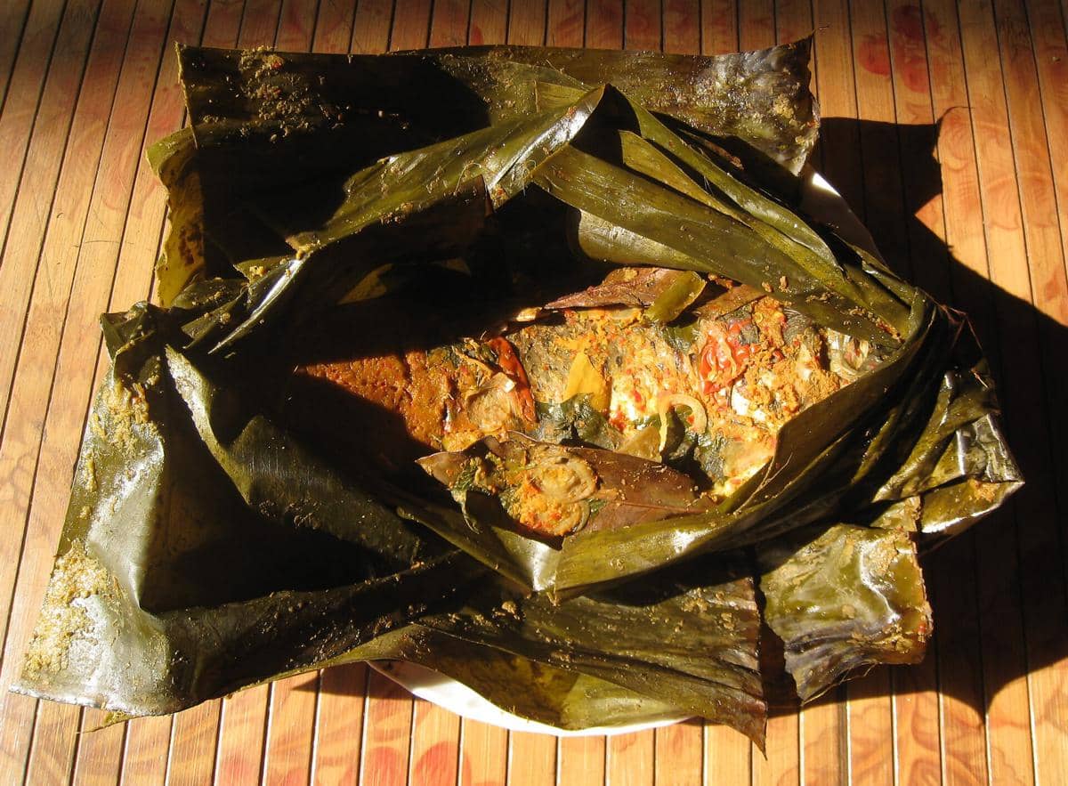 Ilustrasi pais, hidangan tradisional berupa ikan berbumbu yang dibungkus daun pisang dan disajikan di atas piring.