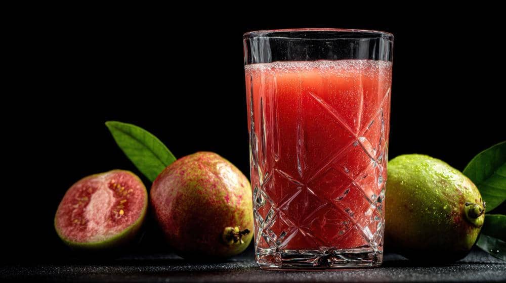 Ilustrasi segelas jus jambu biji merah dengan potongan buah jambu biji segar sebagai minuman sehat dingin.
