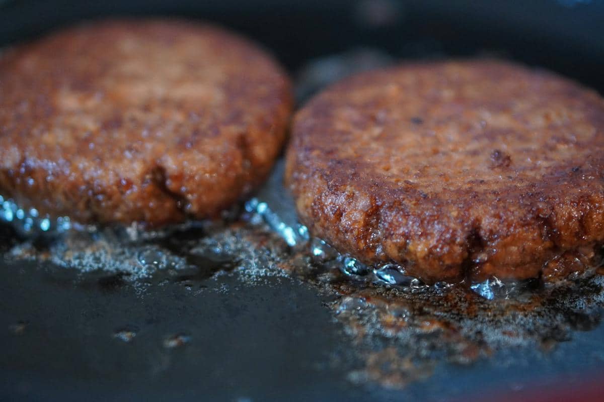 Ilustrasi memasak patty, menggambarkan proses menyiapkan bahan makanan untuk sajian burger rumahan.