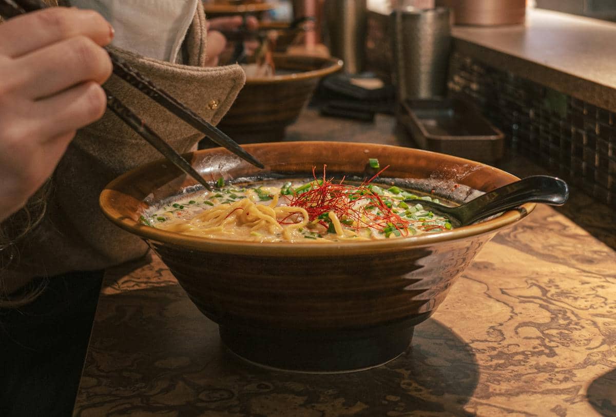 Ilustrasi saffron miso ramen dalam semangkuk sebagai sajian mi berkuah dengan perpaduan cita rasa miso dan saffron.