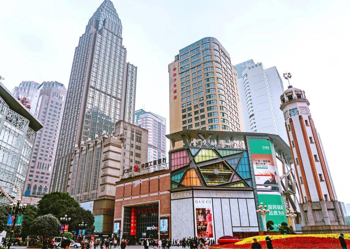 Suasana Jiefangbei Pedestrian Street di Chongqing dengan pejalan kaki melintasi pusat belanja yang dikelilingi gedung tinggi.
