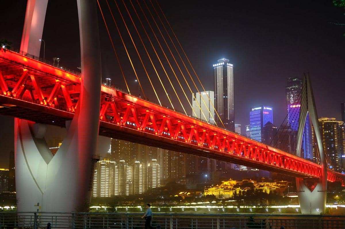 Jembatan Qiansimen membentang di atas sungai, diterangi lampu-lampu pada malam hari dengan latar gedung kota.