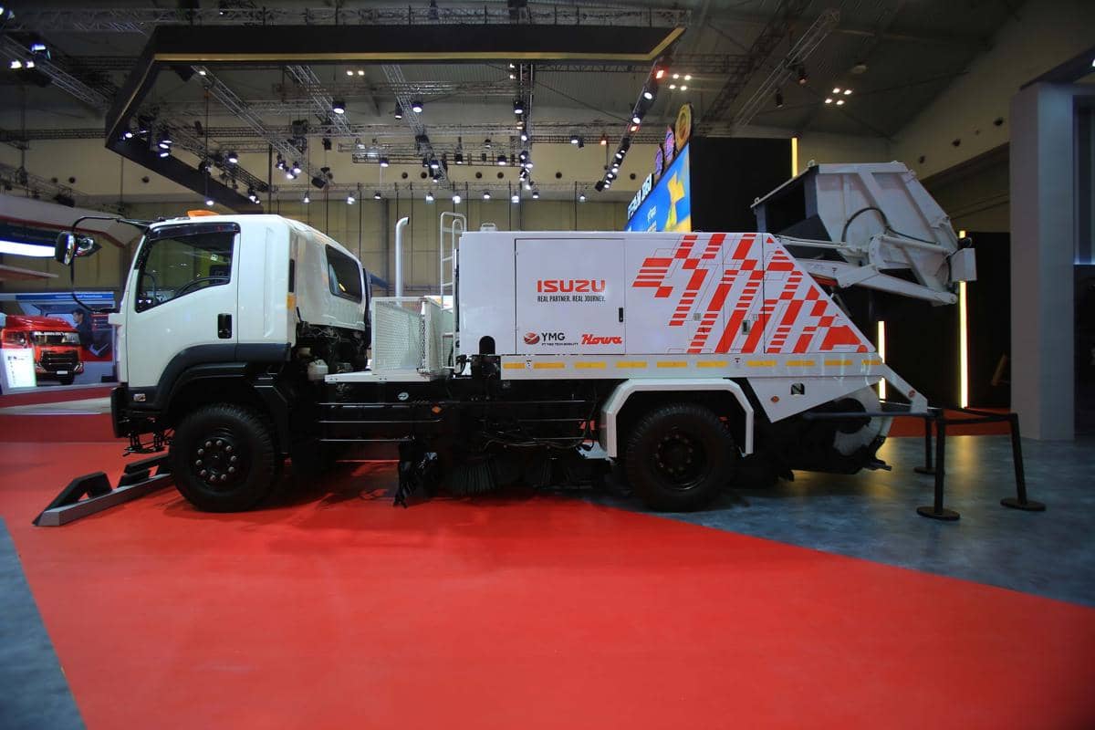 Truk penyapu jalan Isuzu GIGA FVR berwarna putih dengan perlengkapan pembersih jalan terpasang di bagian belakang.