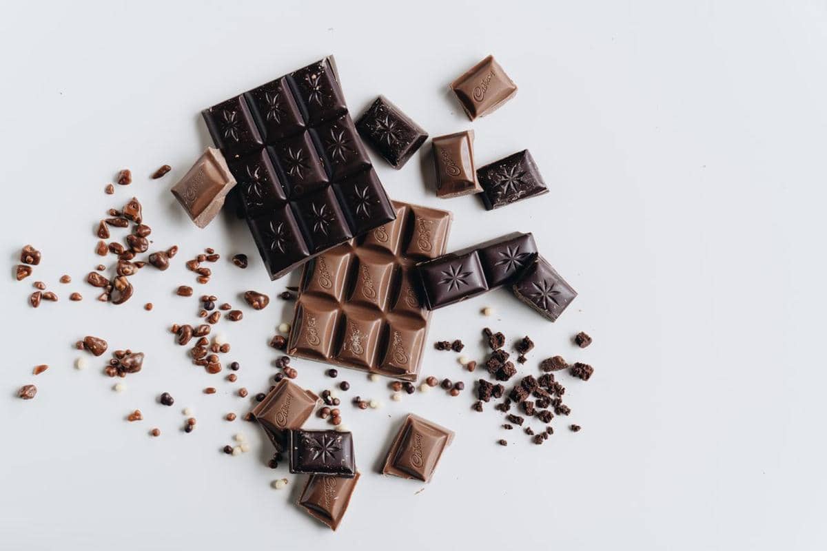 Ilustrasi batang cokelat berwarna cokelat tua dengan potongan kotak-kotak, disajikan sebagai visual makanan manis.