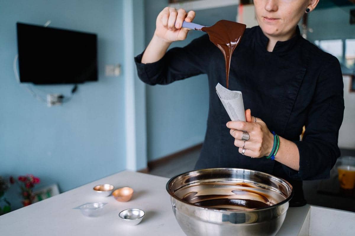 Ilustrasi proses memasukkan cokelat cair ke dalam piping bag sebagai persiapan menghias aneka sajian manis.