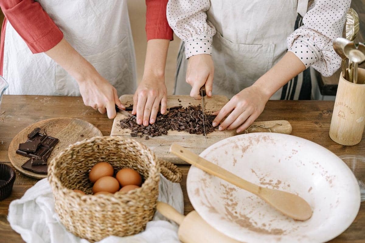 Ilustrasi proses memotong cokelat menjadi beberapa bagian menggunakan pisau di atas permukaan kerja dapur.