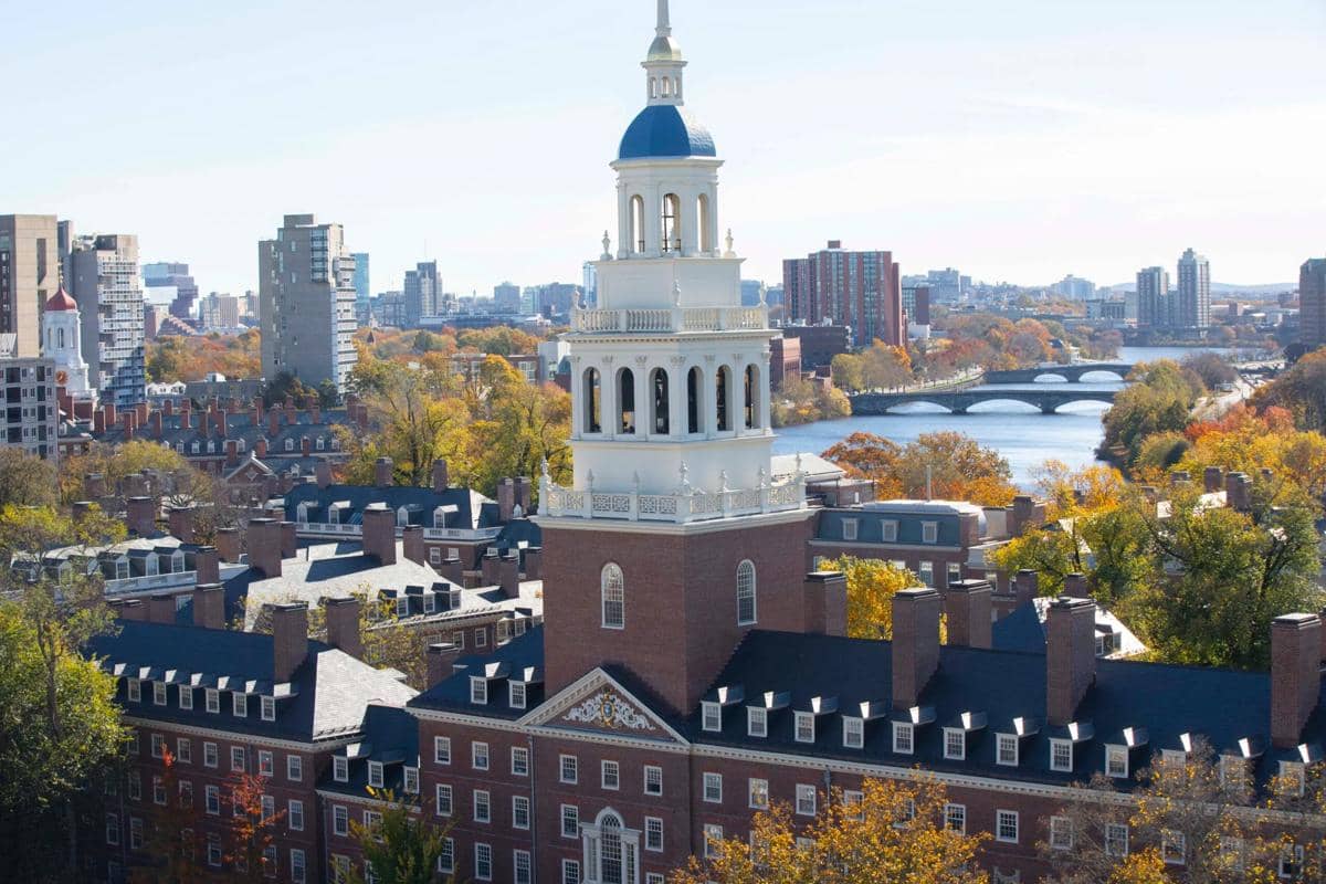 Bangunan kampus Harvard University berbahan bata merah berdiri di antara pepohonan di lingkungan universitas.