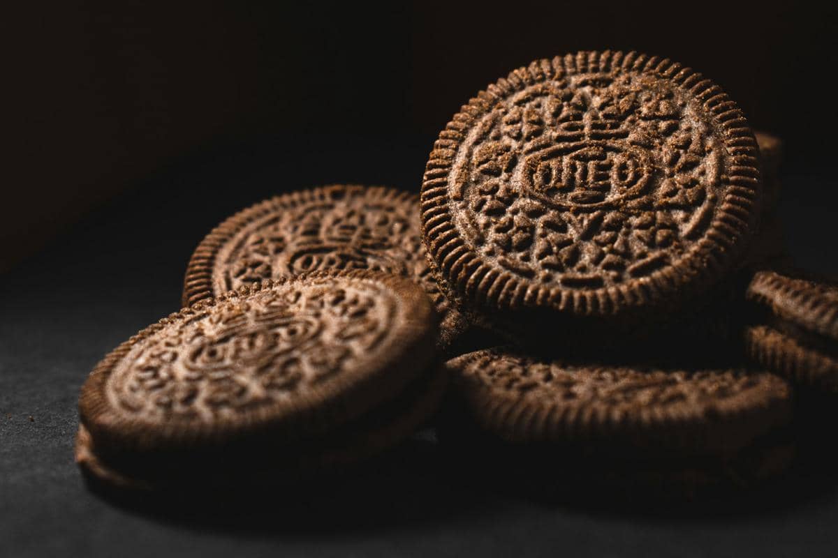 Tumpukan biskuit Oreo berwarna hitam dengan lapisan krim putih, disajikan sebagai ilustrasi makanan ringan.