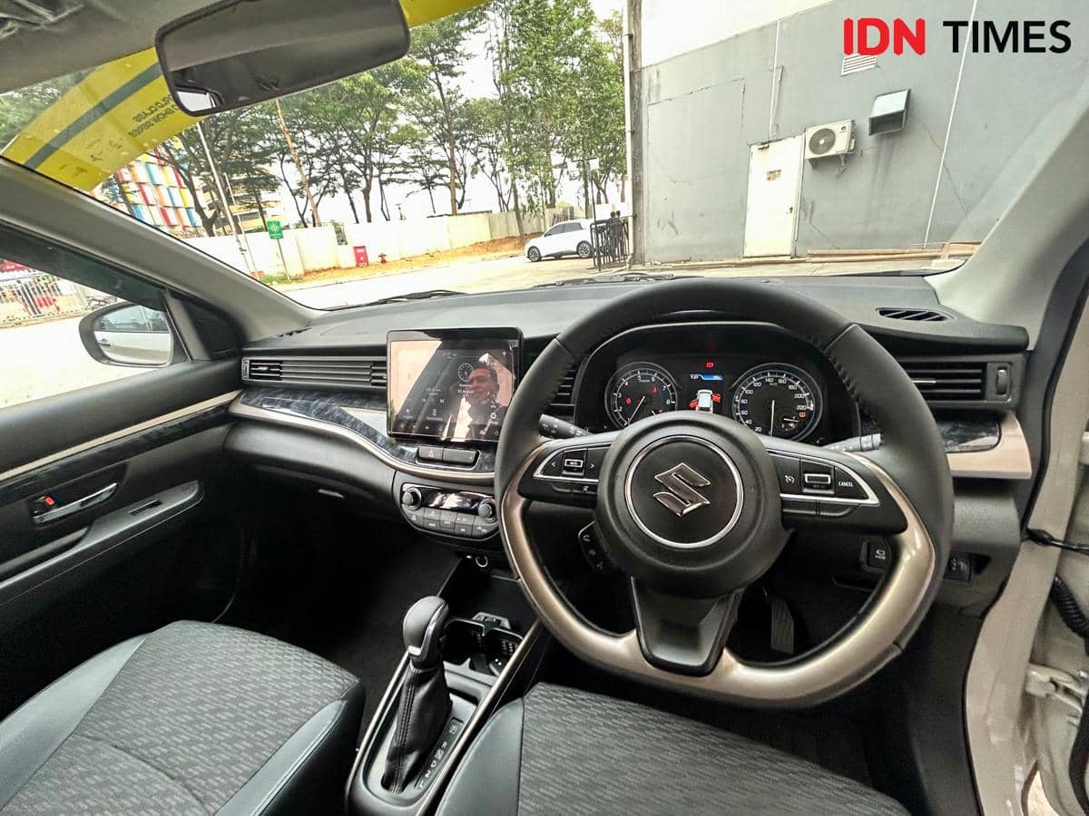 Interior Suzuki XL7 Hybrid dengan dasbor, setir berlogo Suzuki, panel instrumen, layar hiburan, dan kursi depan.