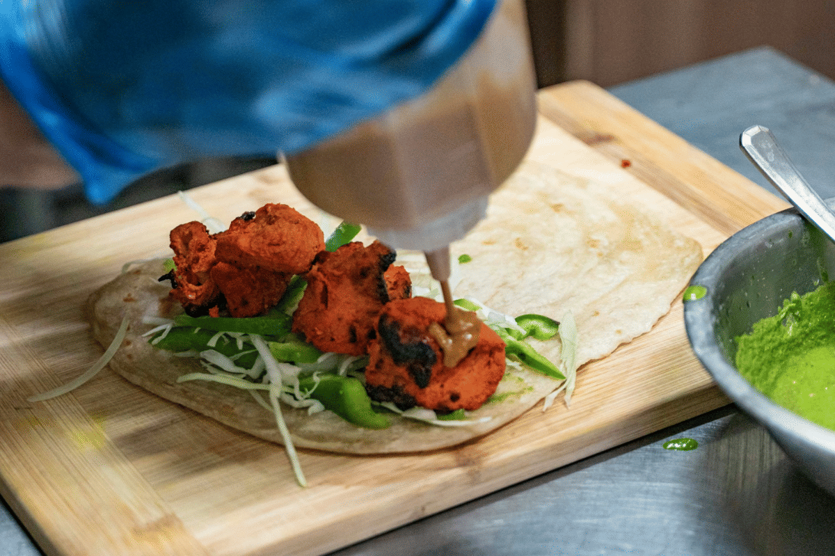 Ilustrasi chicken snack wrap berisi ayam dan sayuran segar dalam tortilla, disajikan sebagai camilan praktis.