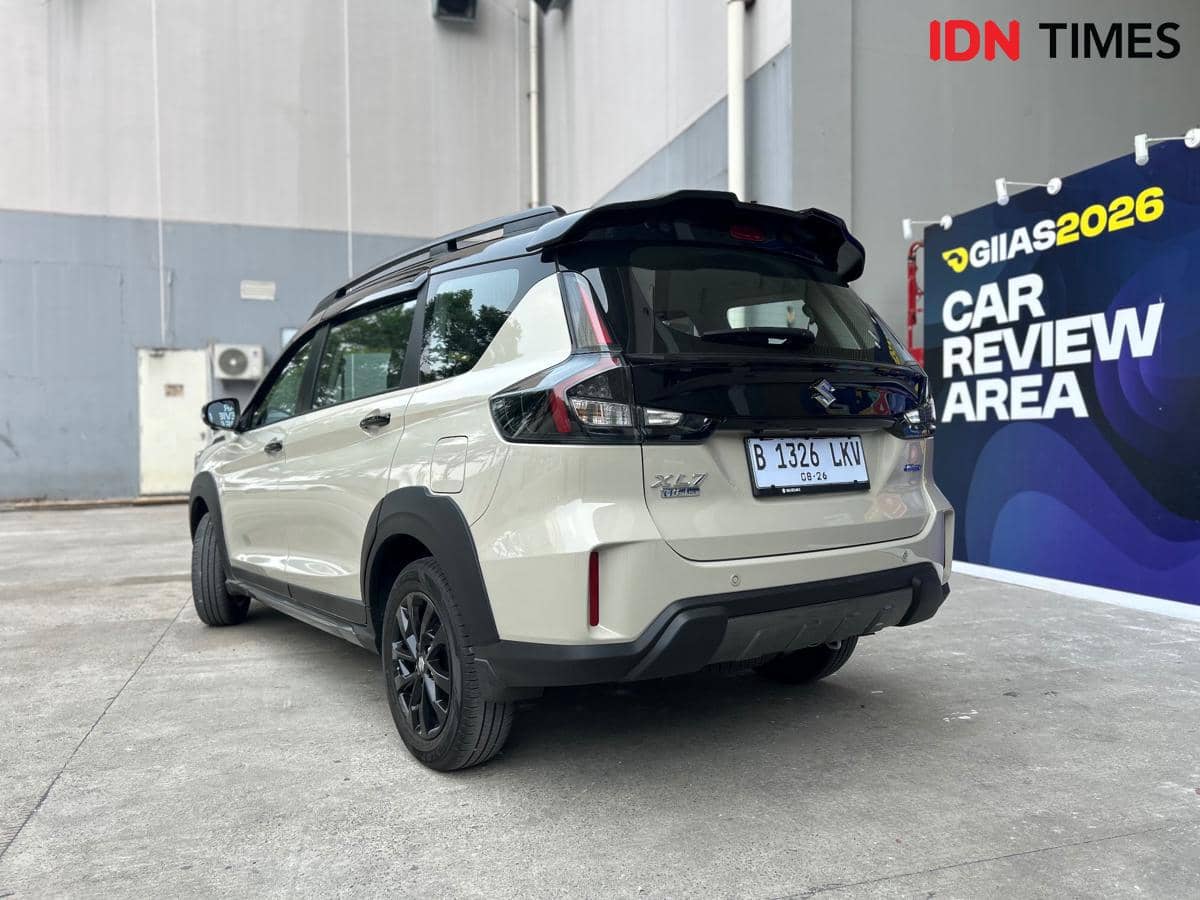 Suzuki New XL7 Hybrid dari belakang, memperlihatkan lampu belakang, kaca bagasi, serta emblem kendaraan.