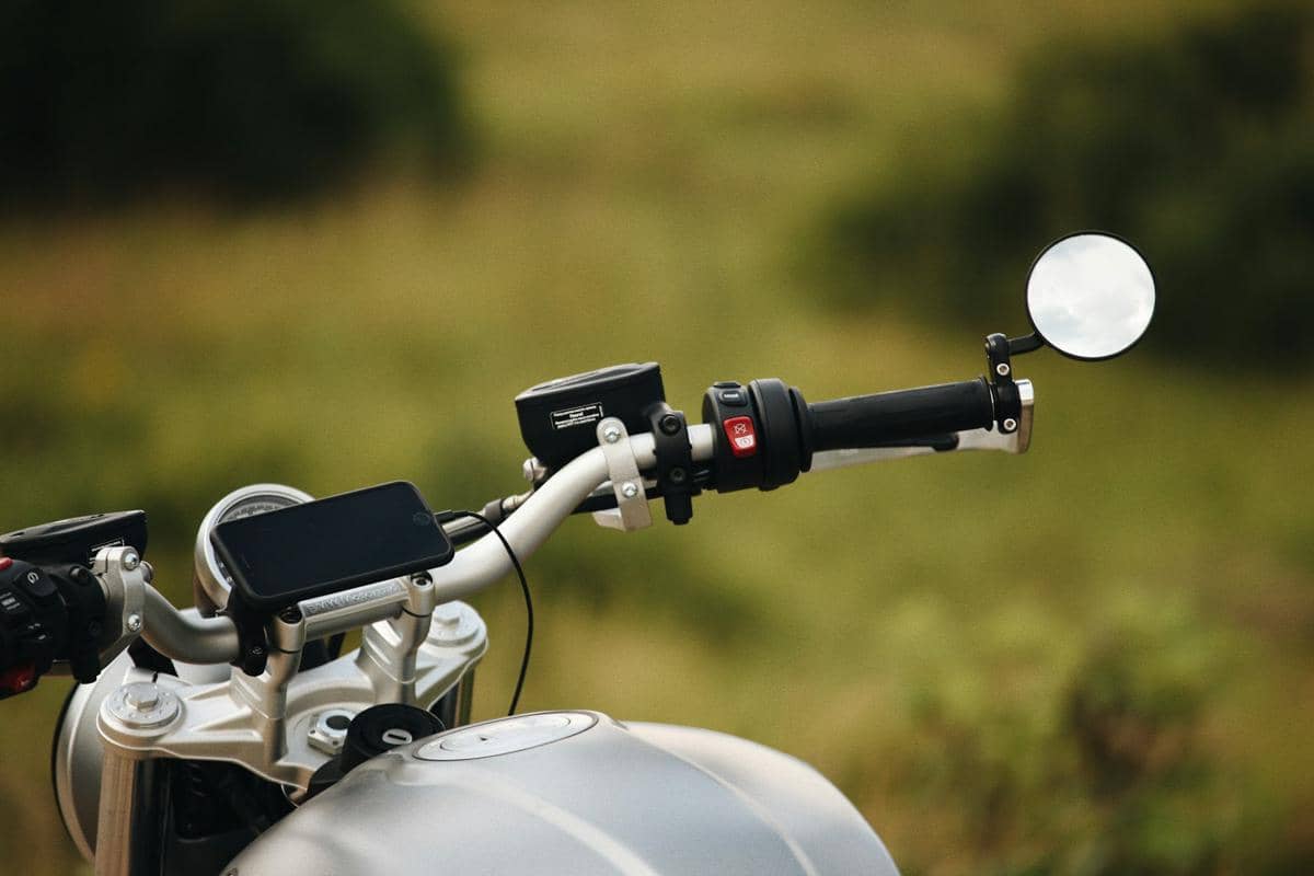 Seorang pengendara mengendarai sepeda motor dengan ponsel terpasang pada holder di bagian setang saat berkendara.