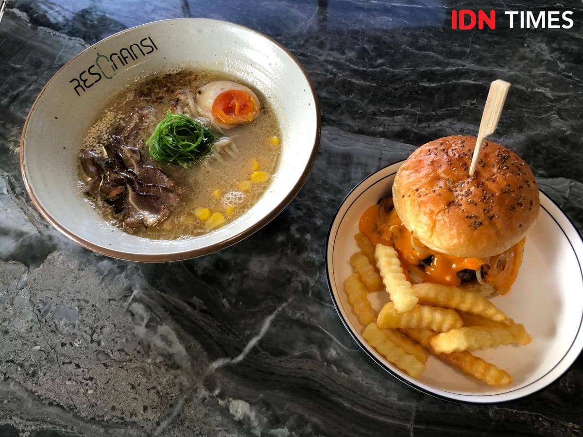 Semangkuk ramen dan burger tersaji sebagai salah satu menu di Resonansi Jogja, dengan pelengkap sayuran dan minuman.