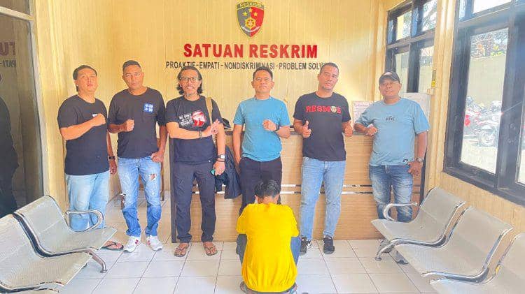 Personel Polresta Kupang Kota menahan pria terduga pelaku asusila di depan latar dinding bertulisan polisi.