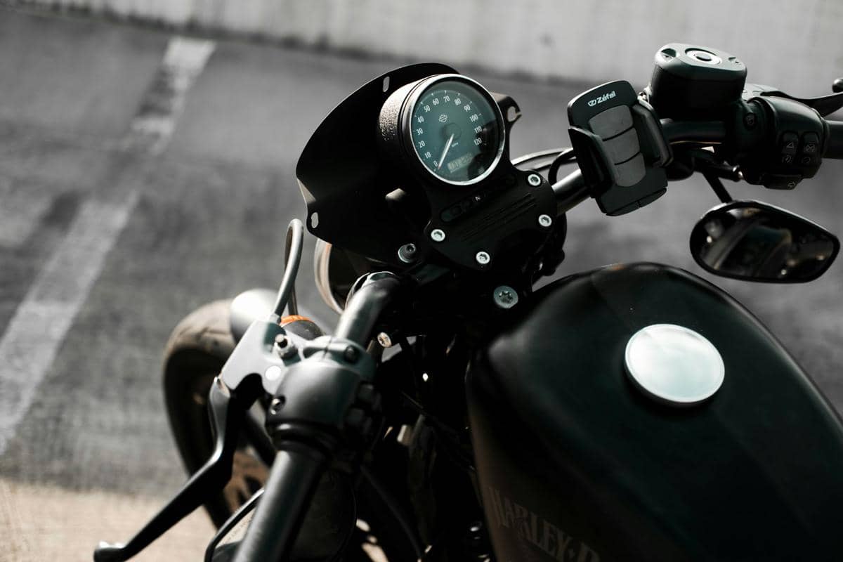 Ponsel pintar terpasang pada holder di setang motor, memperlihatkan penggunaan perangkat untuk navigasi saat berkendara.