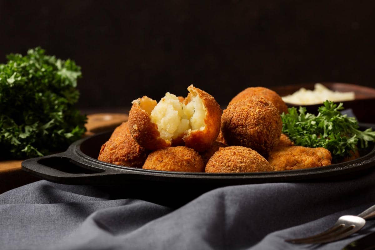 Ilustrasi arancini, bola nasi khas Italia berlapis tepung roti dengan bagian tengah berisi keju meleleh hangat.